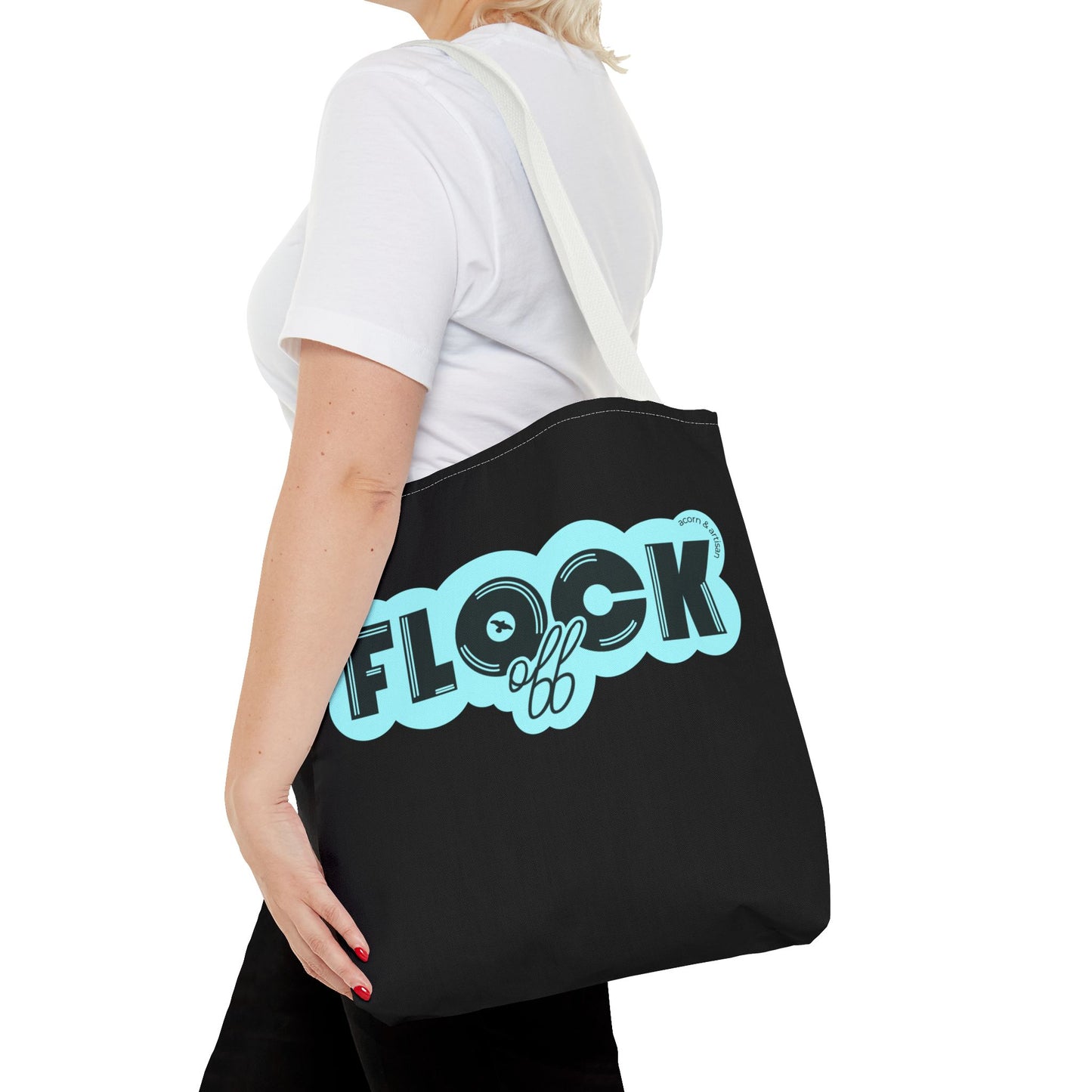 Close-up of the 'Flock Off' tote bag being carried on a person's shoulder, emphasizing the bold lettering, durable black canvas, and comfortable white straps