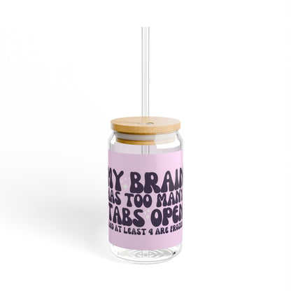 16oz reusable glass tumbler with bamboo lid and straw featuring the humorous quote 'My Brain Has Too Many Tabs Open (And at Least 9 Are Frozen)' in bold, playful typography on a pastel pink background. Perfect for multitaskers with a sense of humor.