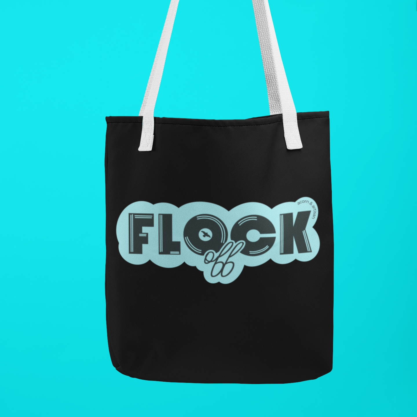 Black canvas tote bag with bold aqua lettering reading 'Flock Off,' held by a hand against a vibrant blue background. A stylish and cheeky accessory for everyday use.