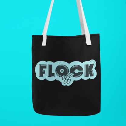 Black canvas tote bag with bold aqua lettering reading 'Flock Off,' held by a hand against a vibrant blue background. A stylish and cheeky accessory for everyday use.