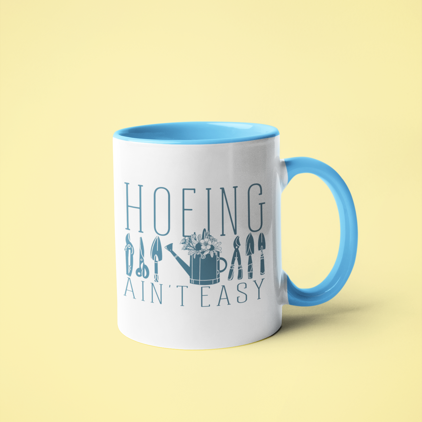 White ceramic mug featuring the phrase 'Hoeing Ain't Easy' with garden tool illustrations, displayed against a vibrant yellow background. Perfect for gardeners and plant enthusiasts.