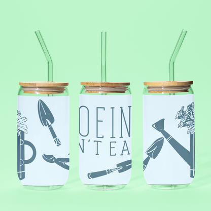 Reusable glass tumbler with 'Hoeing Ain't Easy' gardening design, displayed on a green background showing all sides, including the bold typography and playful illustrations.