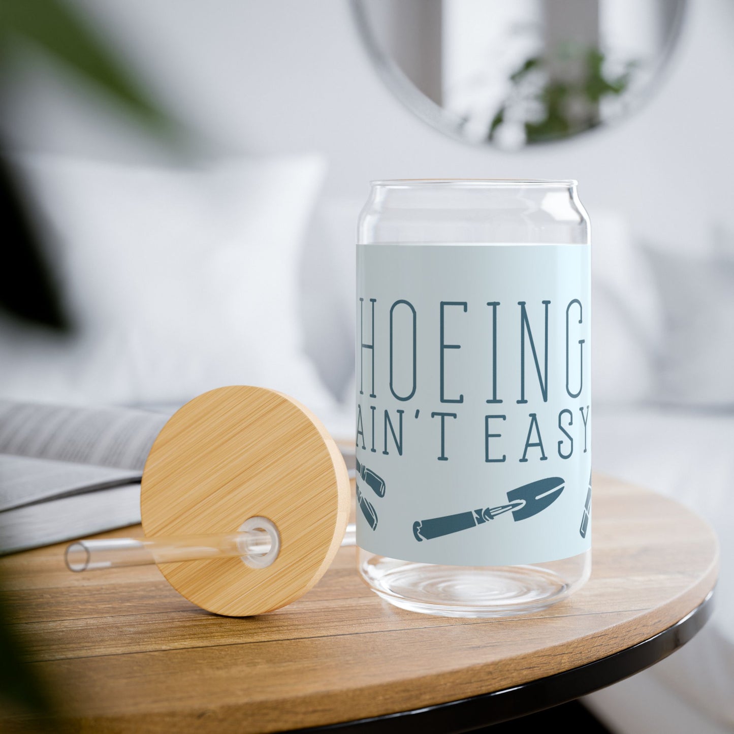 Funny gardening glass tumbler with 'Hoeing Ain't Easy' design, styled in a cozy lifestyle setting with gardening props and plants.