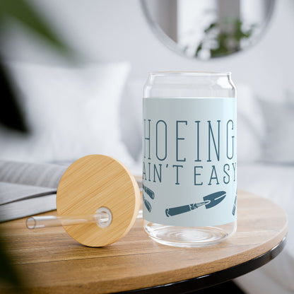 Funny gardening glass tumbler with 'Hoeing Ain't Easy' design, styled in a cozy lifestyle setting with gardening props and plants.