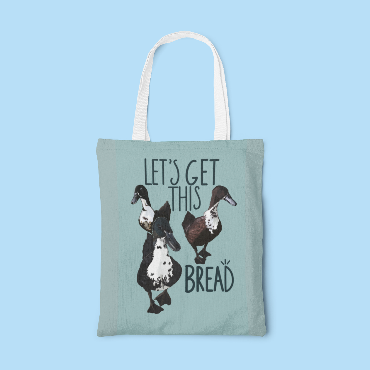 Natural canvas tote bag featuring the playful phrase 'Let’s Get This Bread' in bold typography with a whimsical bread illustration. Perfect for grocery runs, daily errands, or as a fun gift for foodies and achievers.