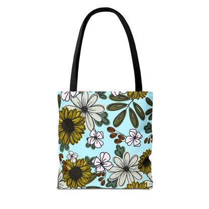 Close-up of the floral tote bag showcasing intricate sunflower and wildflower illustrations in warm, earthy tones on a soft blue background. Made with durable canvas material.