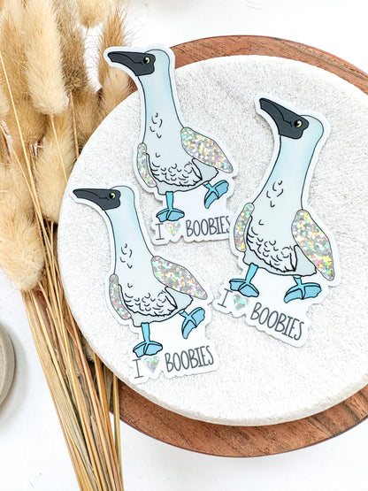 Blue footed boobie sticker with text below: I heart boobies. Wings of the birds are glitter. 