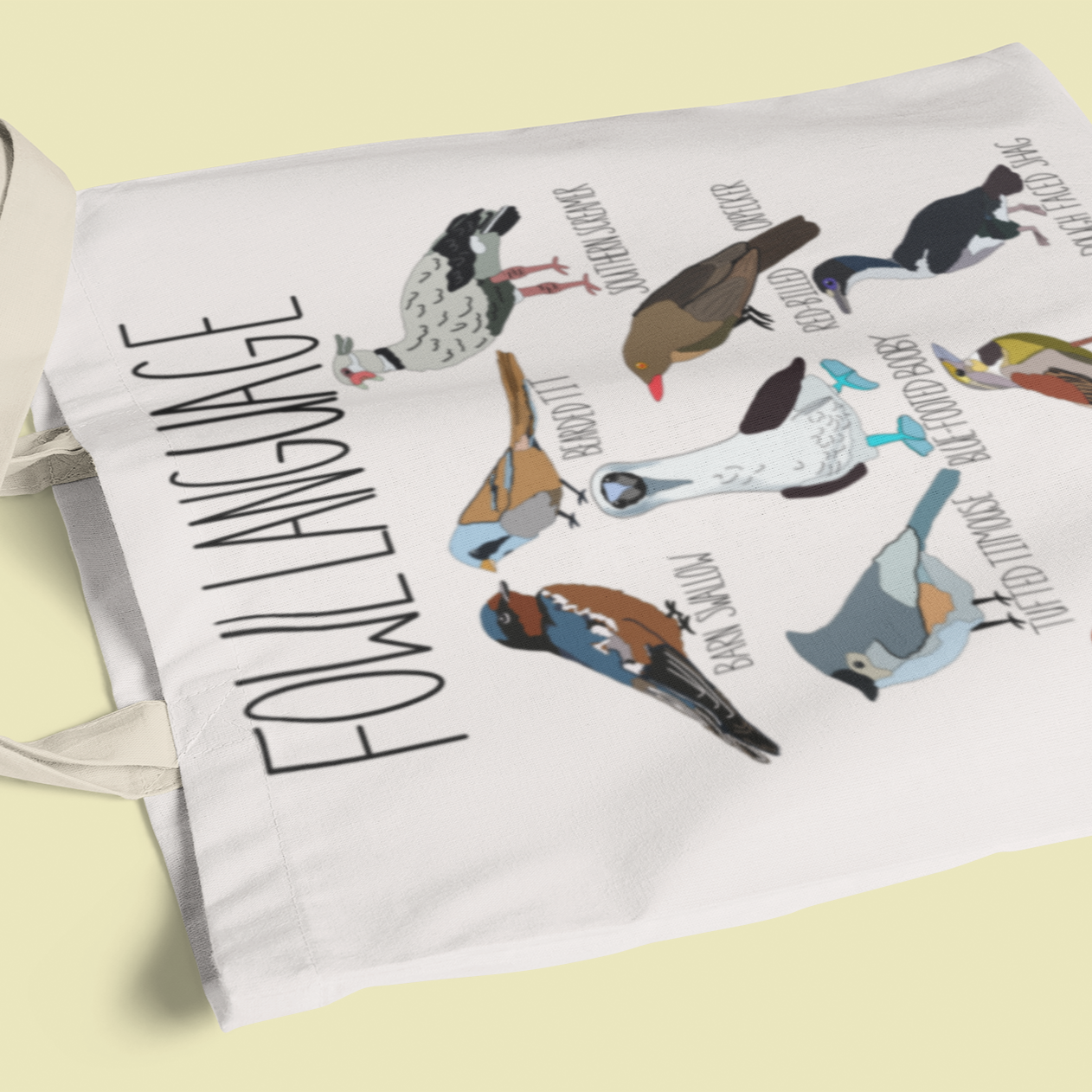 canvas tote bag featuring the playful 'Fowl Language' design with illustrations of birds like the blue-footed booby and dickcissel. Displayed on a light background, perfect for bird lovers and pun enthusiasts